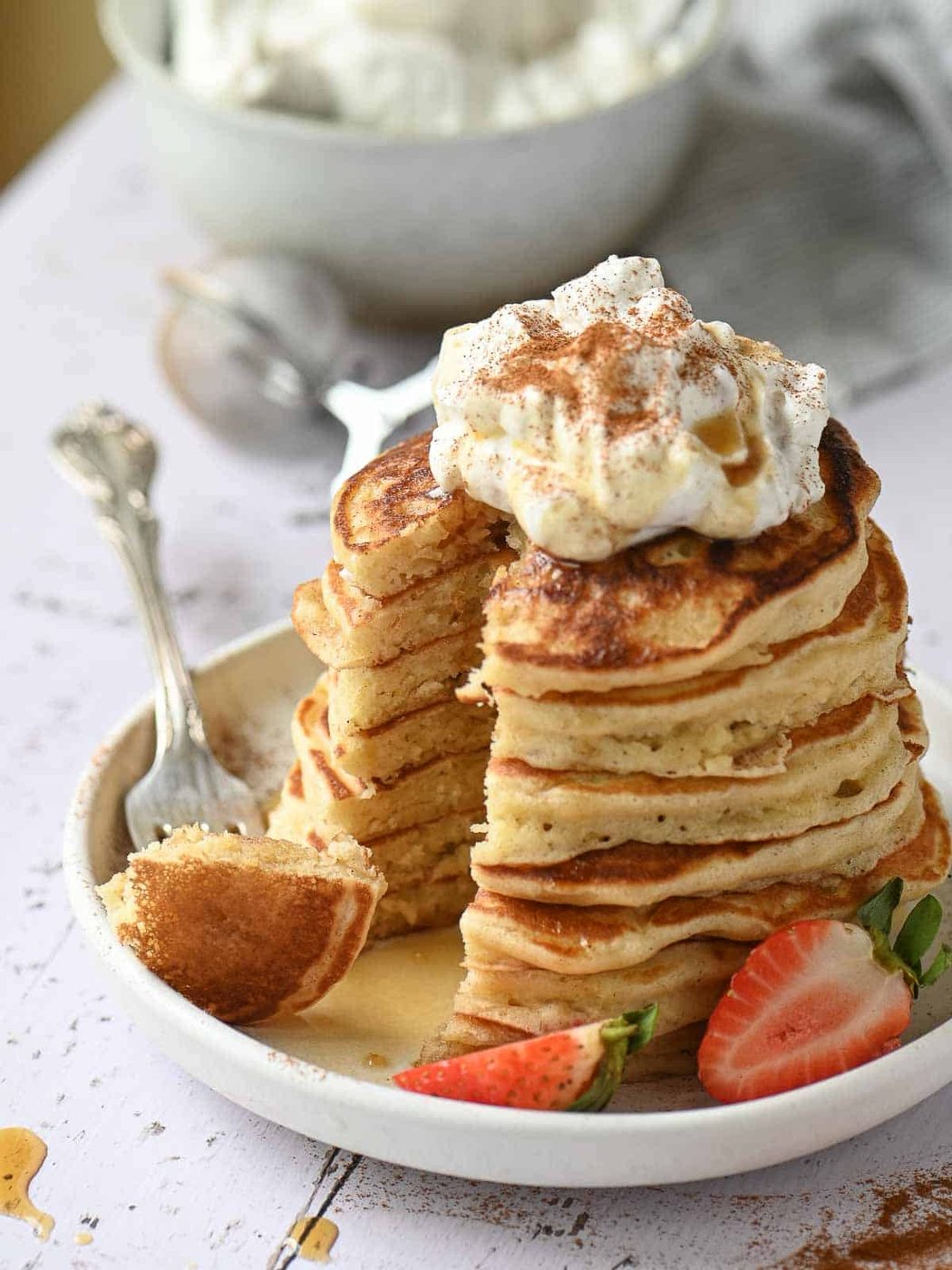 A stack of cinnamon pancakes cut with a piece on a fork to the left.