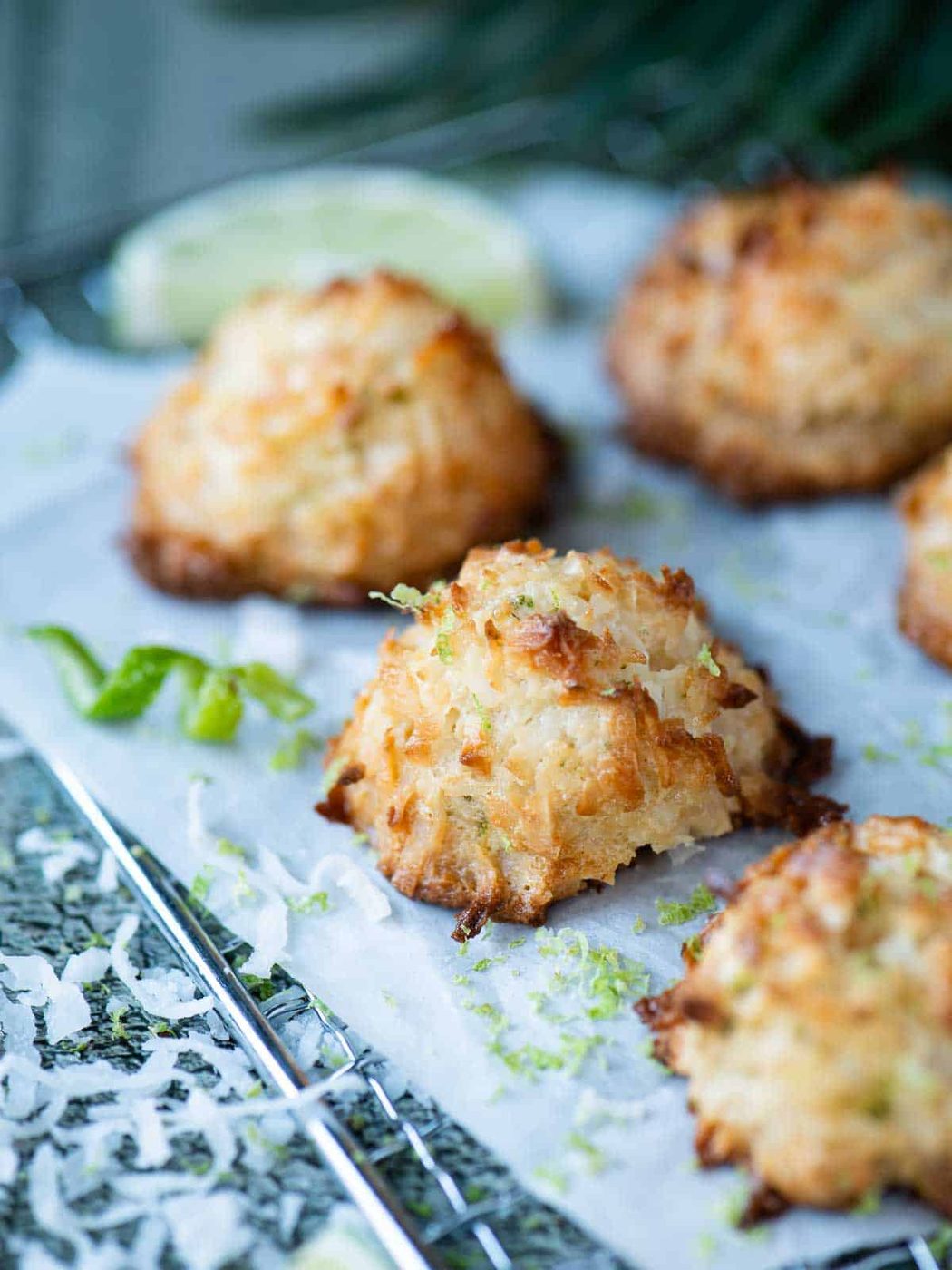 Coconut macaroons on a wire rack with lime zest and coconut around it.