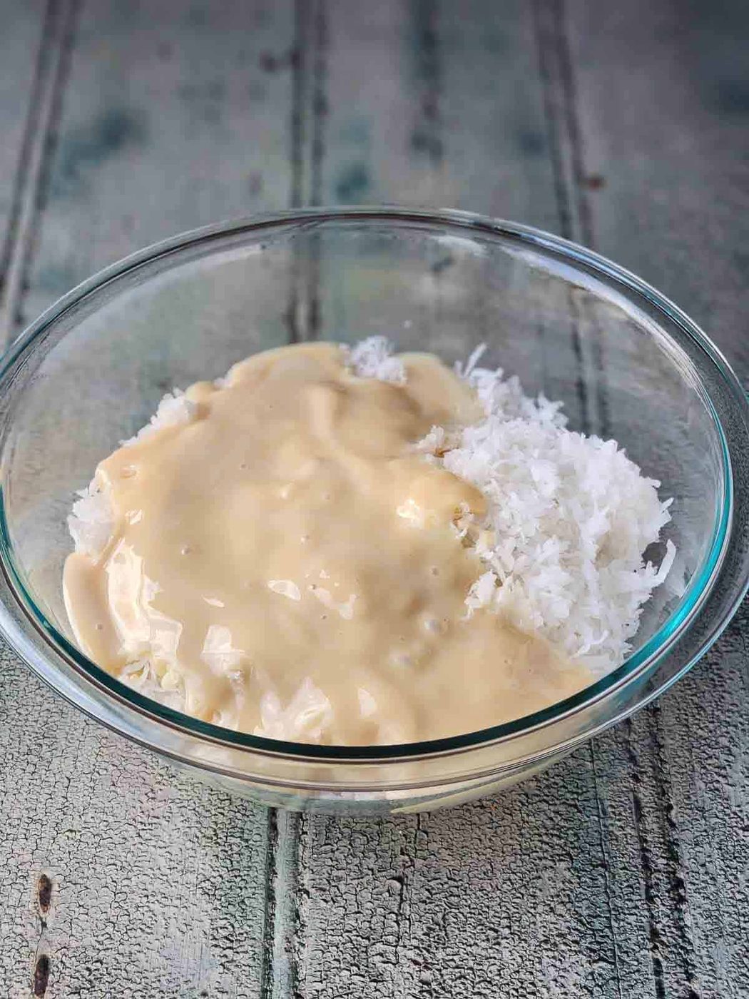 Coconut and condensed milk in a clear bowl.