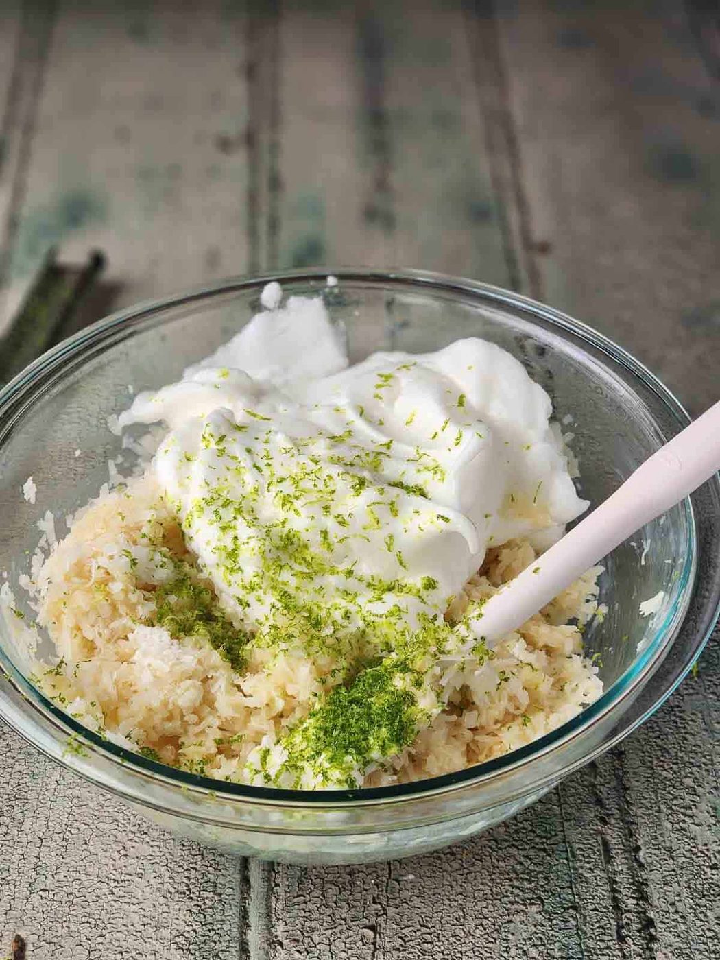 Egg whites and batter for coconut macaroons in a clear bowl.