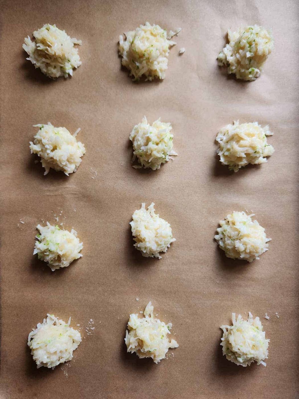 Dropped mounds of macaroon batter on parchment paper.