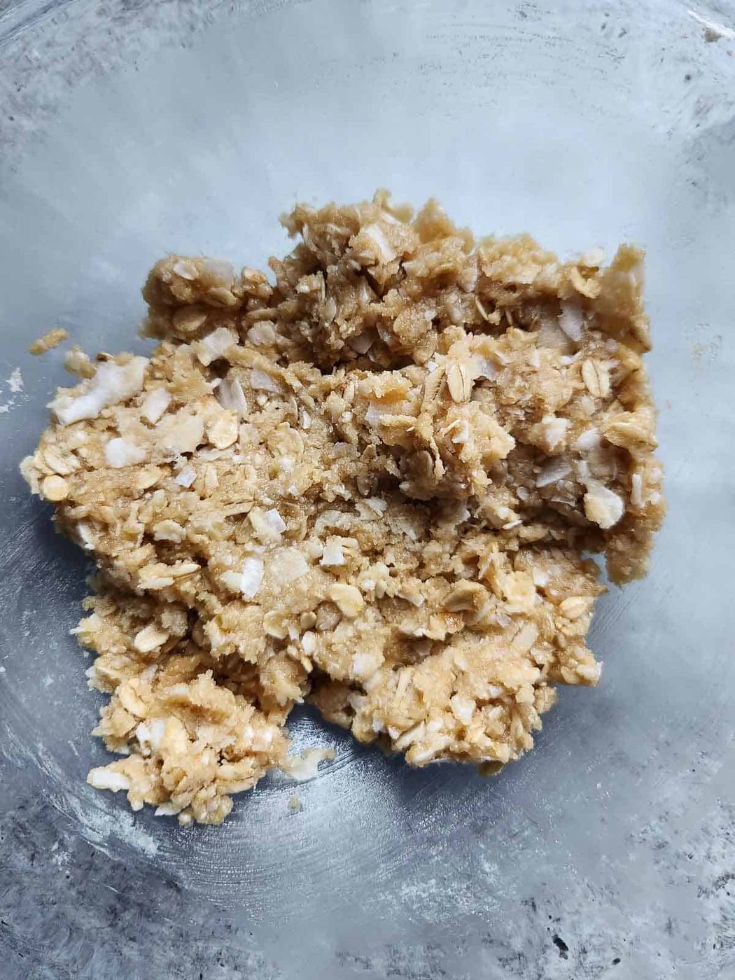 Batter for coconut oatmeal cookies in a clear bowl.