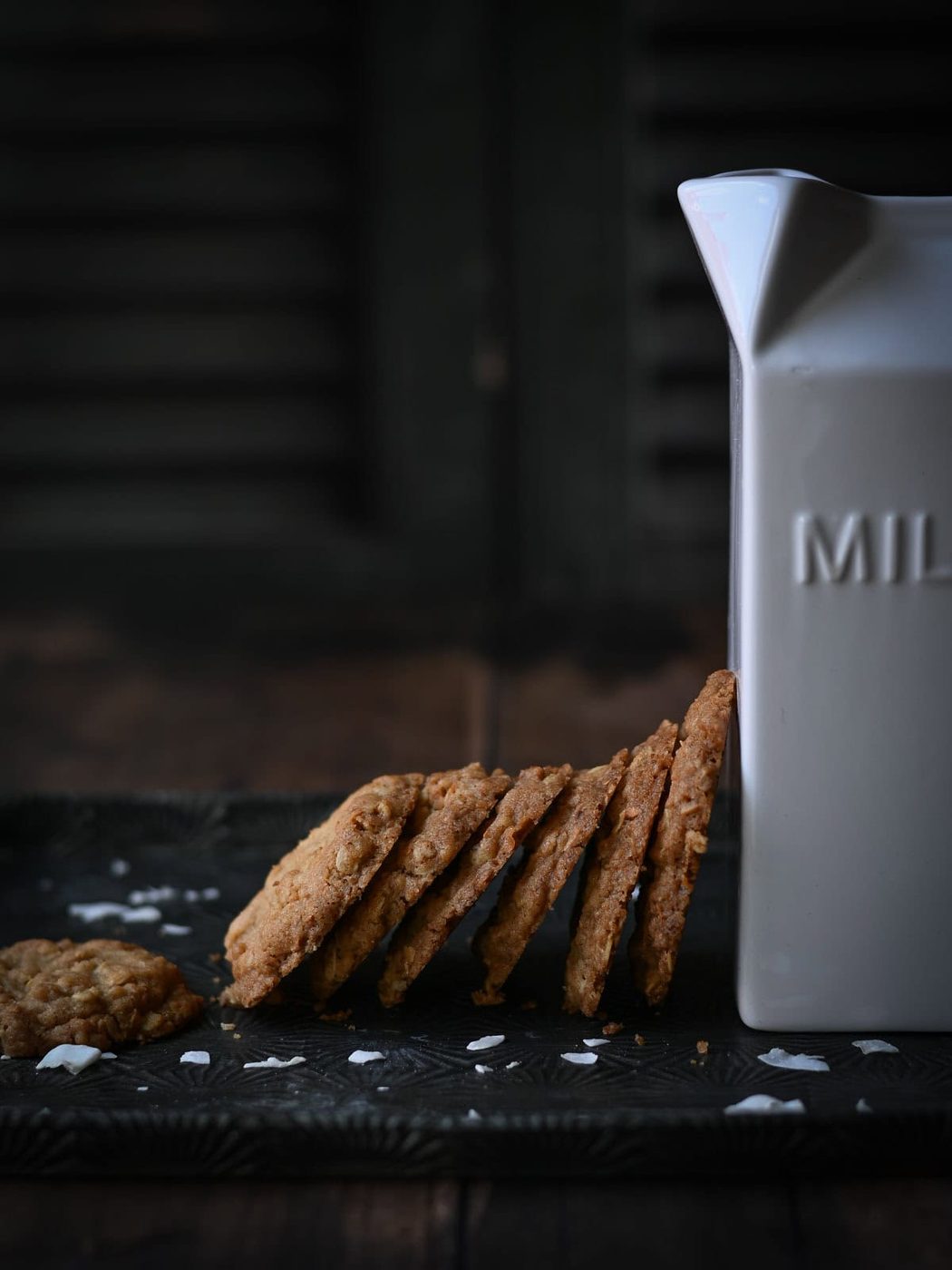 Coconut cookies leaned up against a white milk carton.