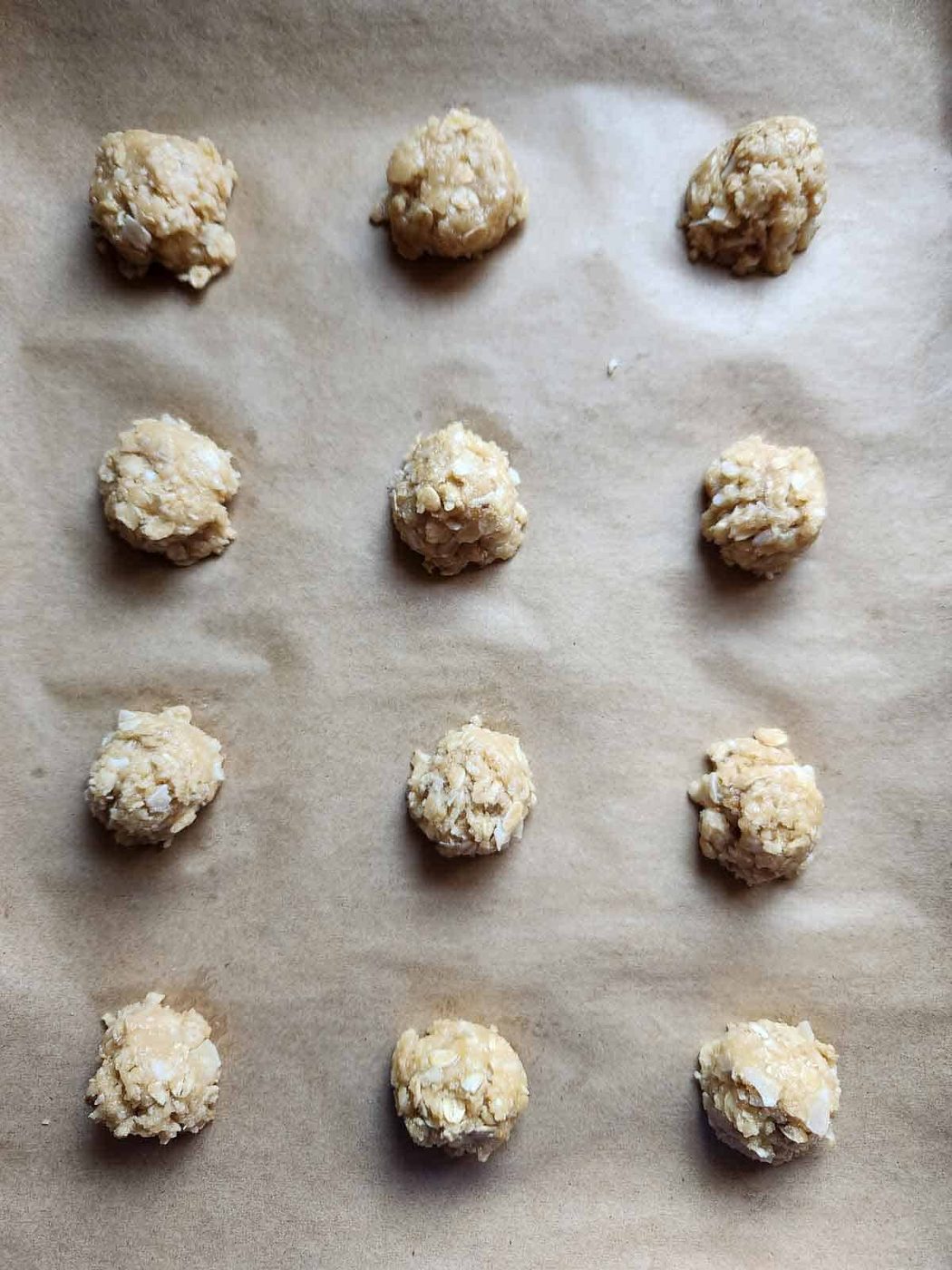 Cookie batter dropped on a parchment lined baking sheet.