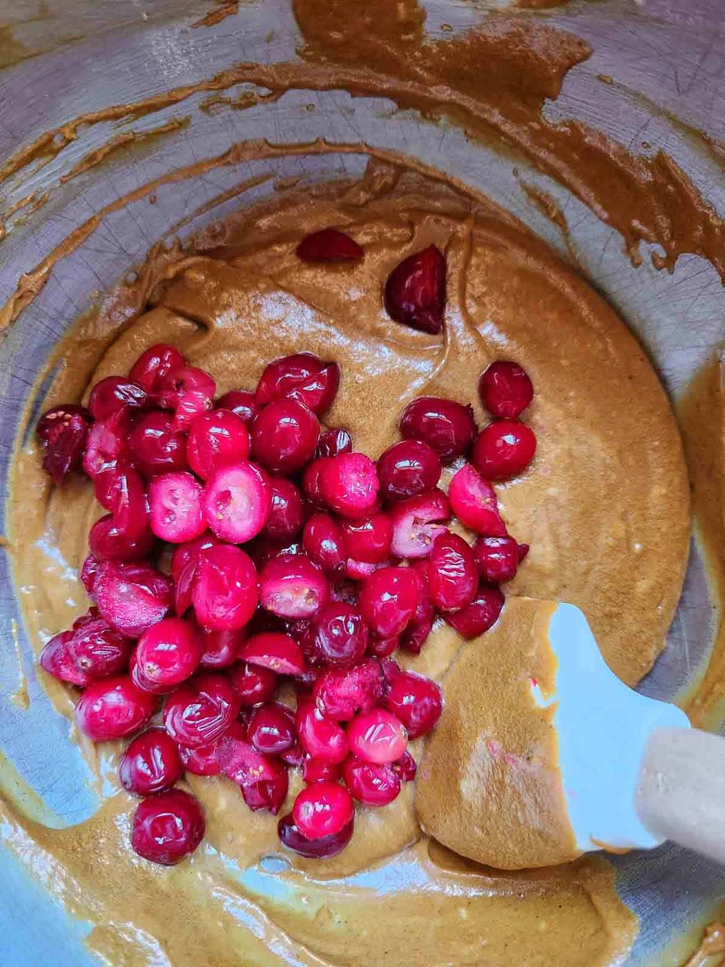 Cranberries with batter in a metal bowl.