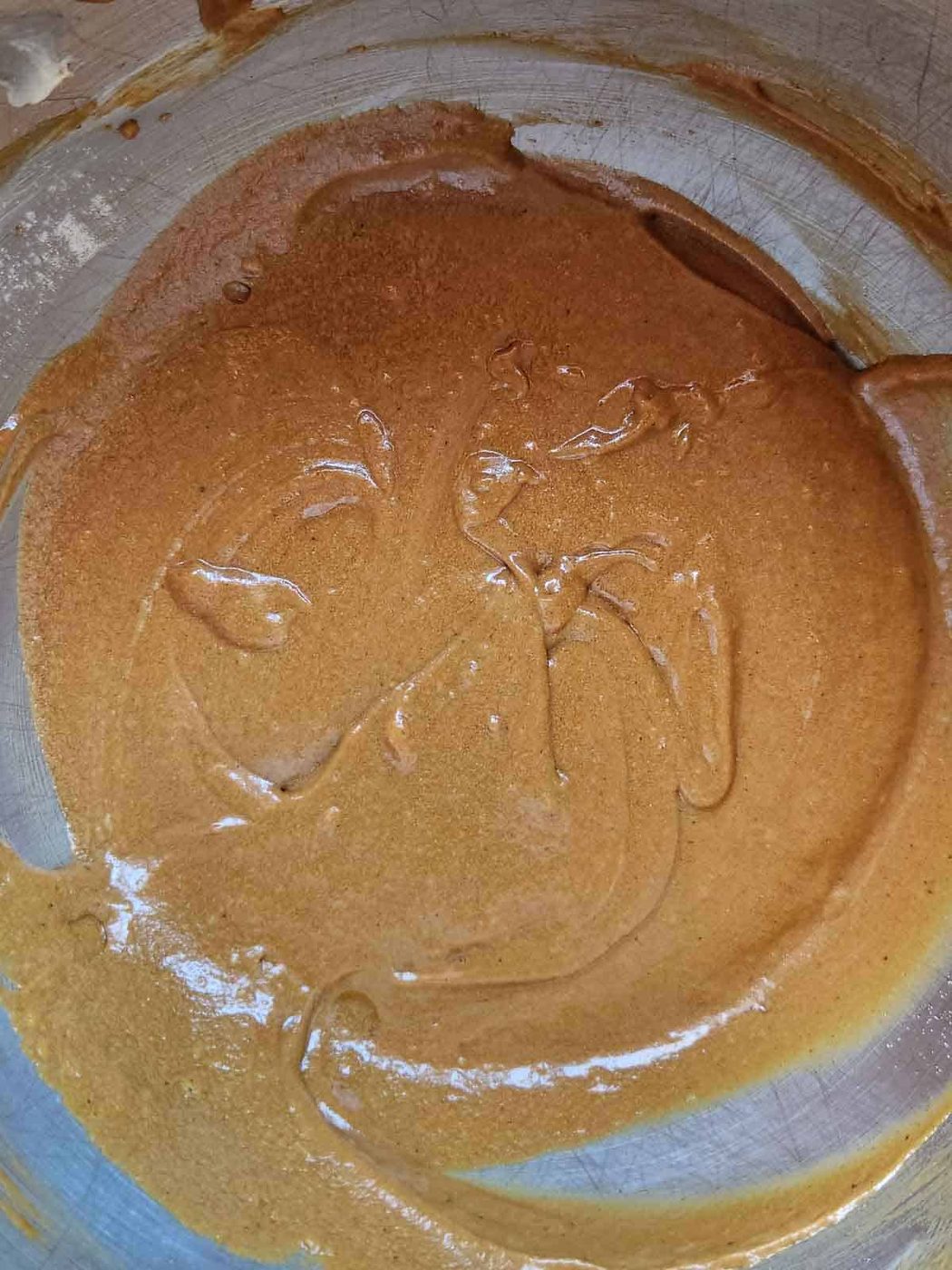 Batter for gingerbread loaf in a metal bowl with molasses.