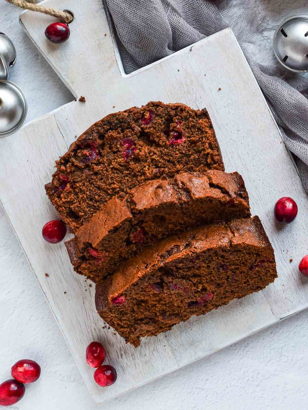 Overhead of 3 slices of cranberry gingerbread loaf on grey board.