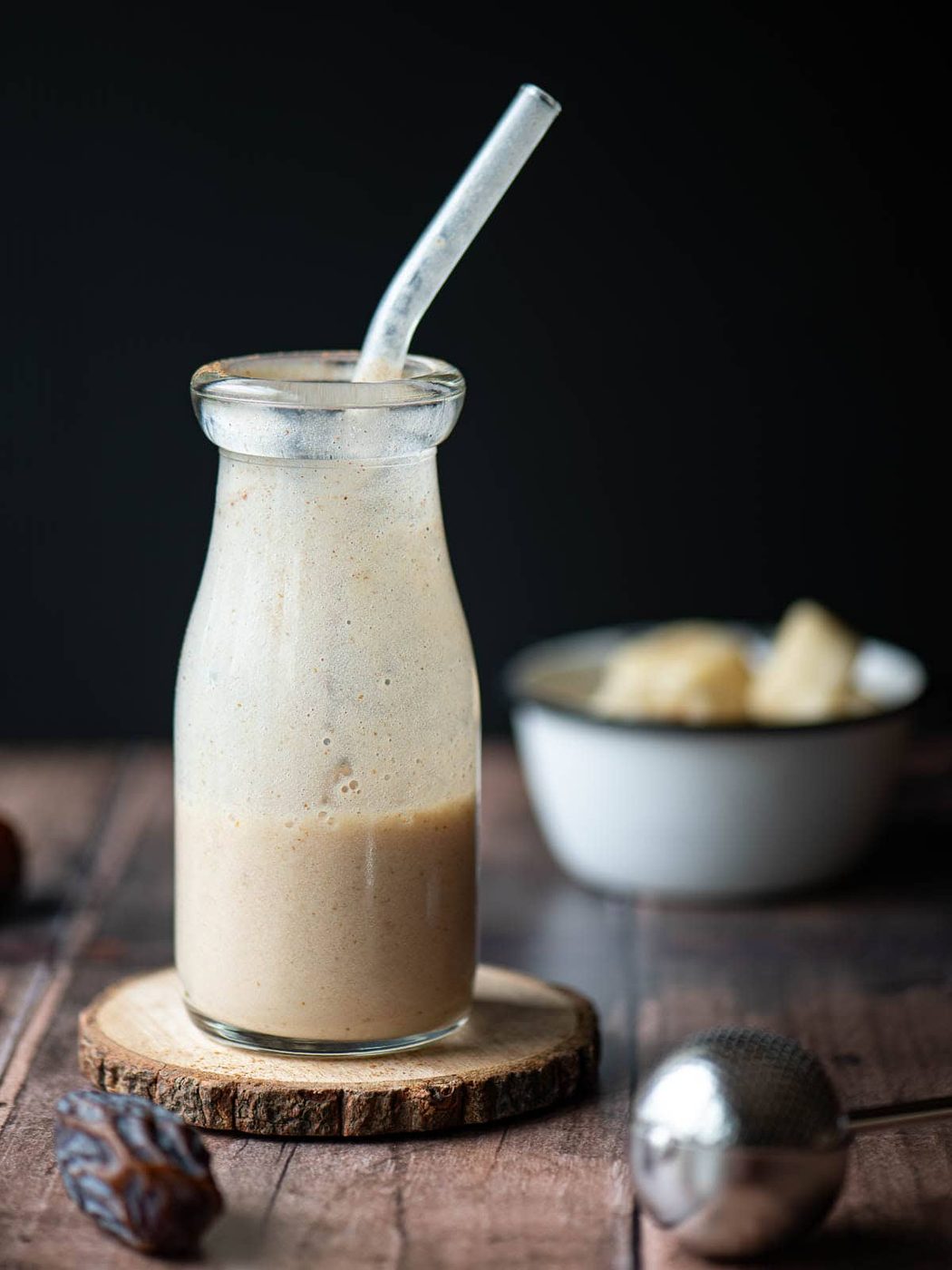 Half drunk smoothie in a clear jug on a wood surface.