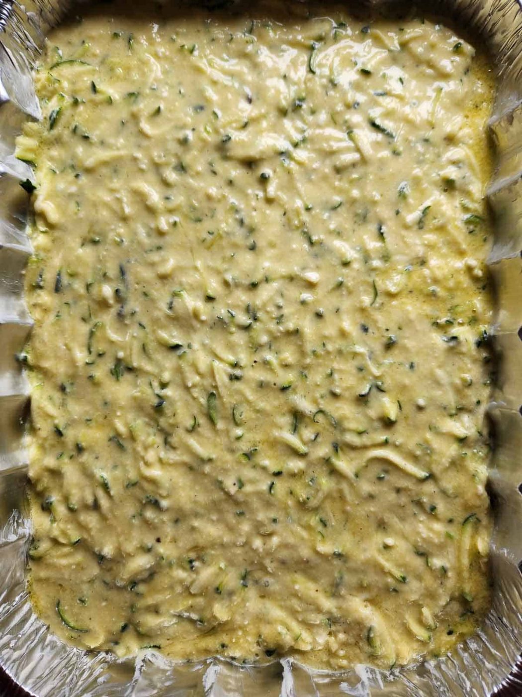 Batter for zucchini pie in a metal pan.