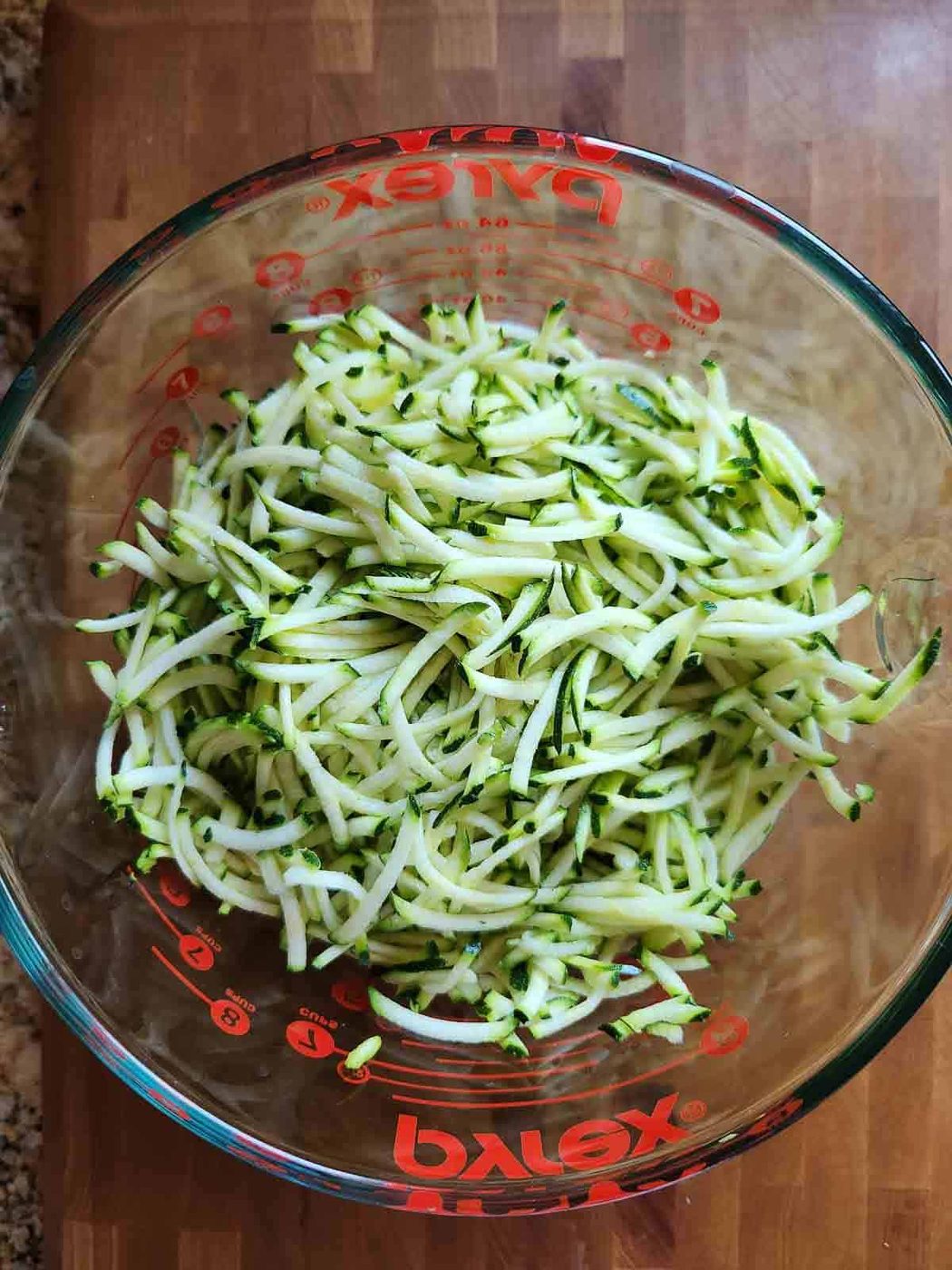 Shredded zucchini in a clear bowl.