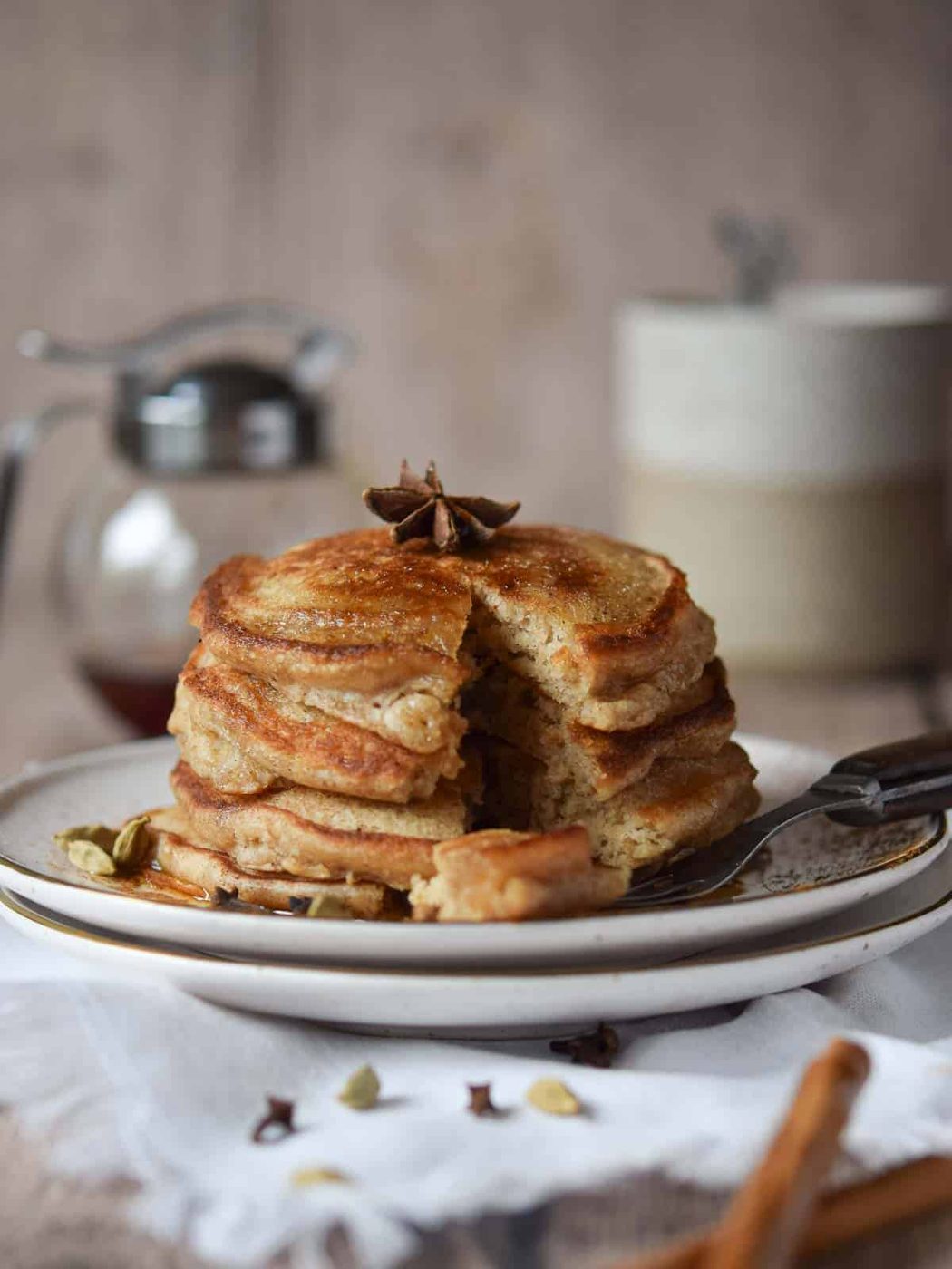 Stack of chai pancakes on a plate with a forkfull taken out.