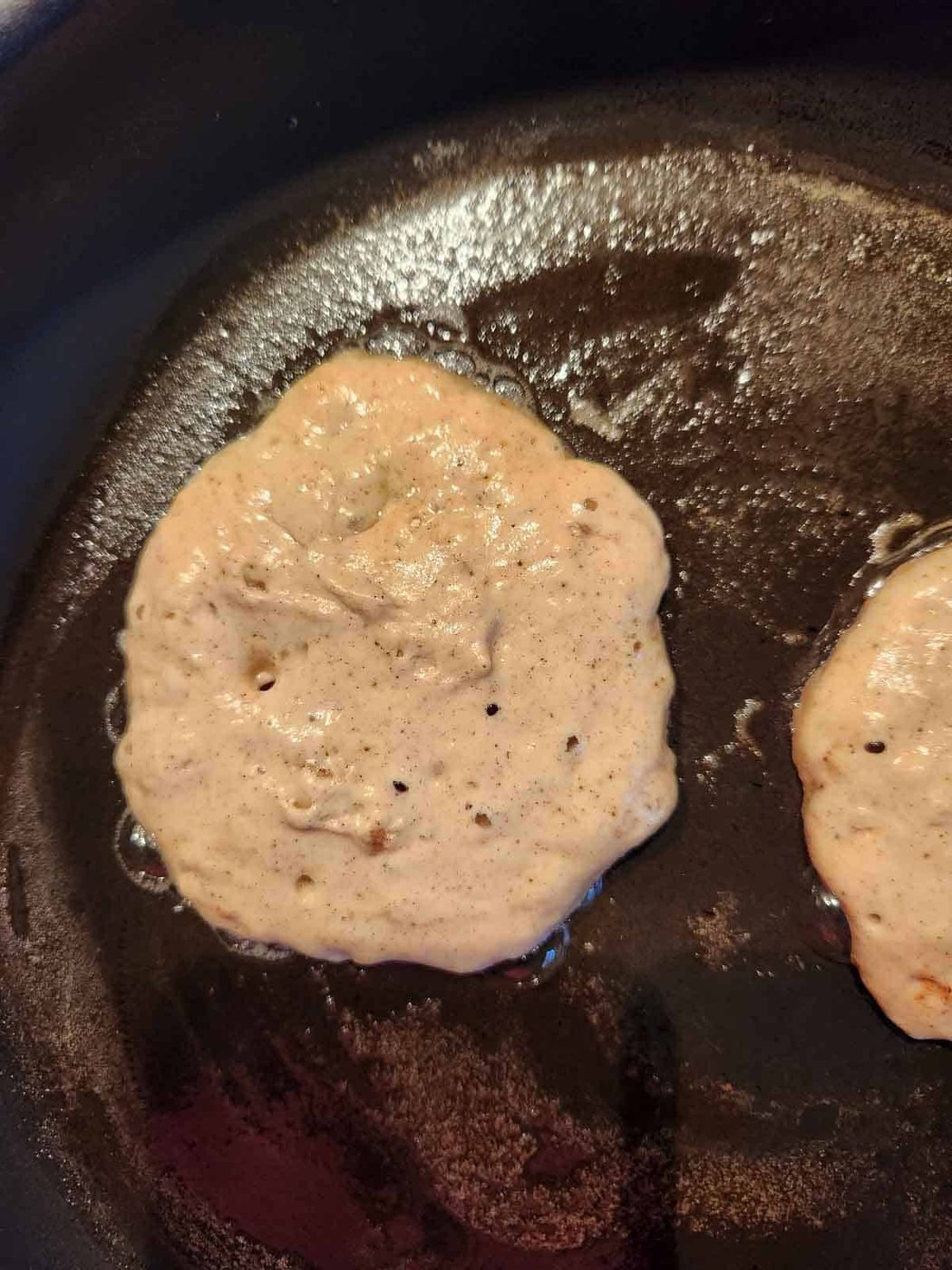 Pancakes are cooked in a buttered skillet.