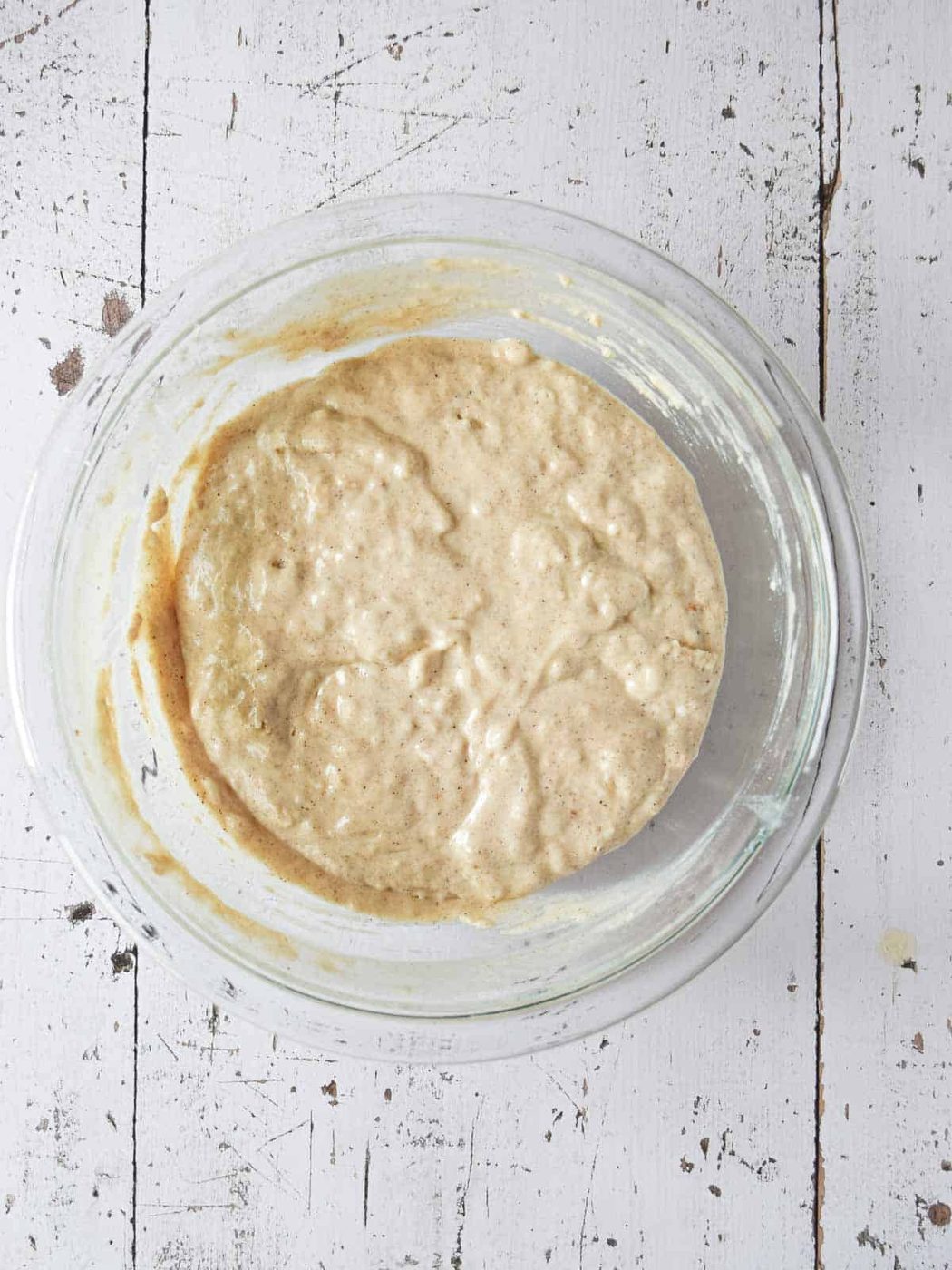 Batter for chai spiced pancakes in a clear bowl.