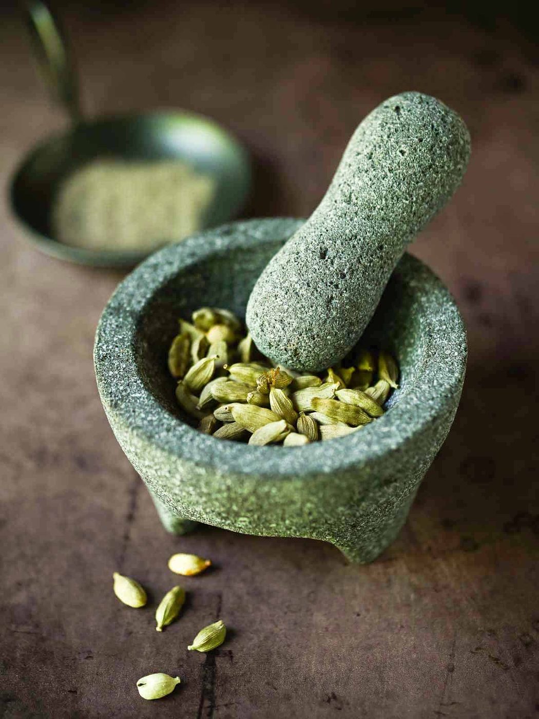 Cardamom pods in a mortar with a pestle.