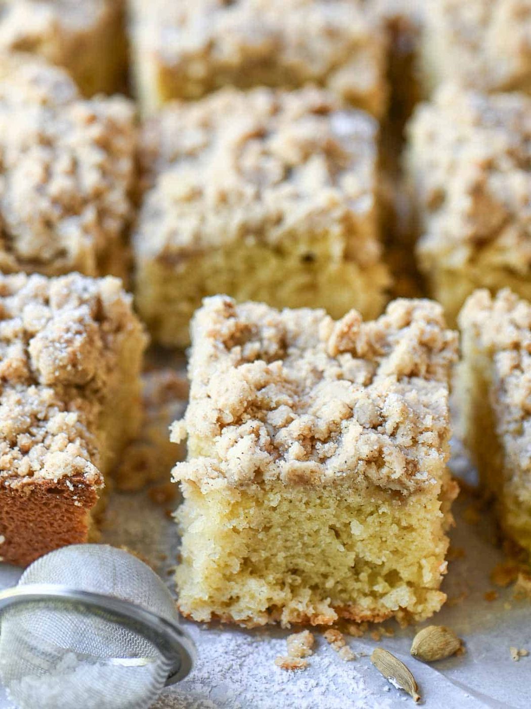 A square of coffee cake with crumb topping on parchment paper.