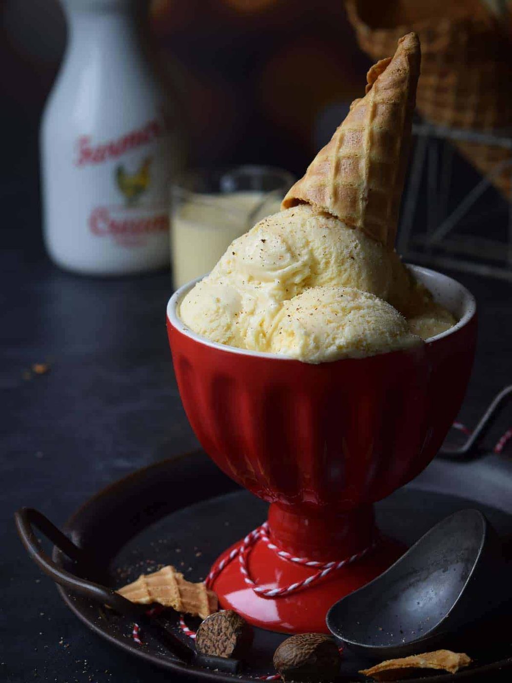Ice cream in a red cup with an ice cream cone on top.