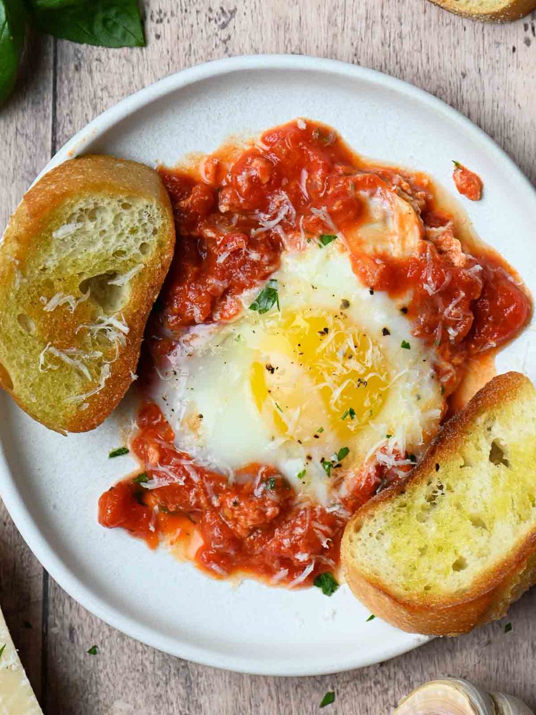 Overview of eggs, sauce and bread on a white plate.