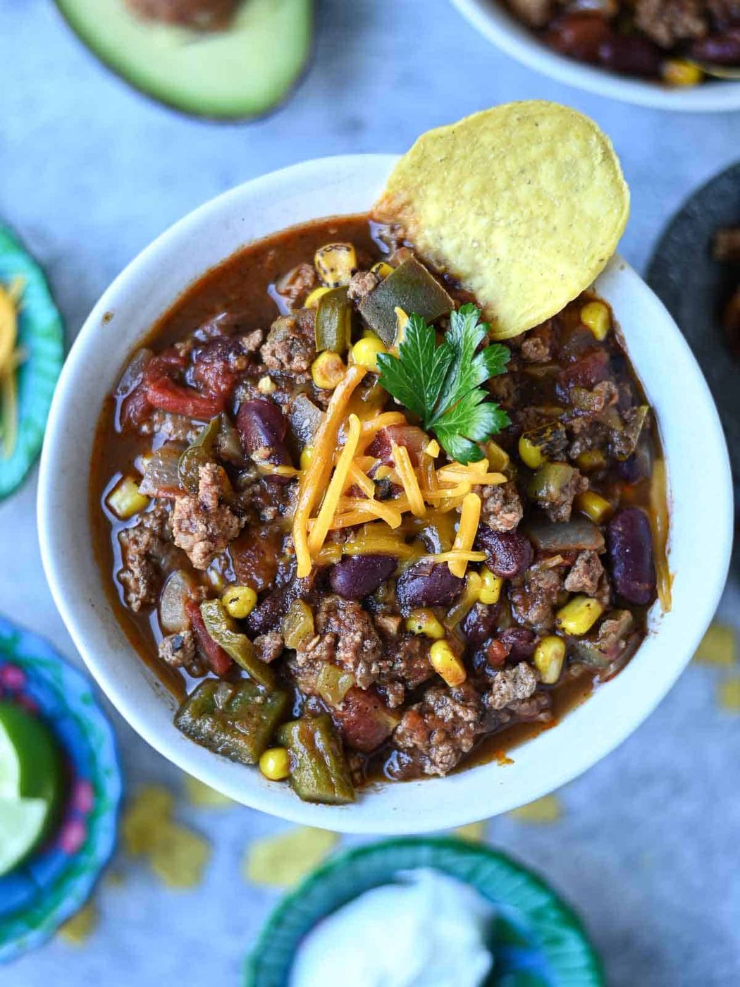 Overhead view of turkey chili in a white bowl with cheese.