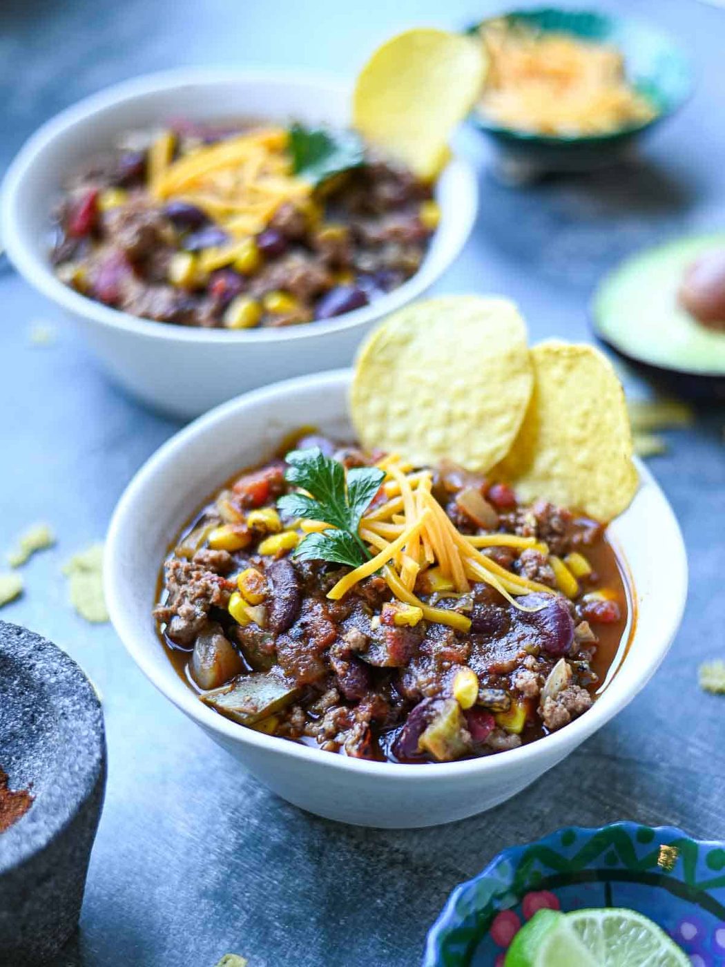 Fire-roasted chili in white bowls on a blue surface.