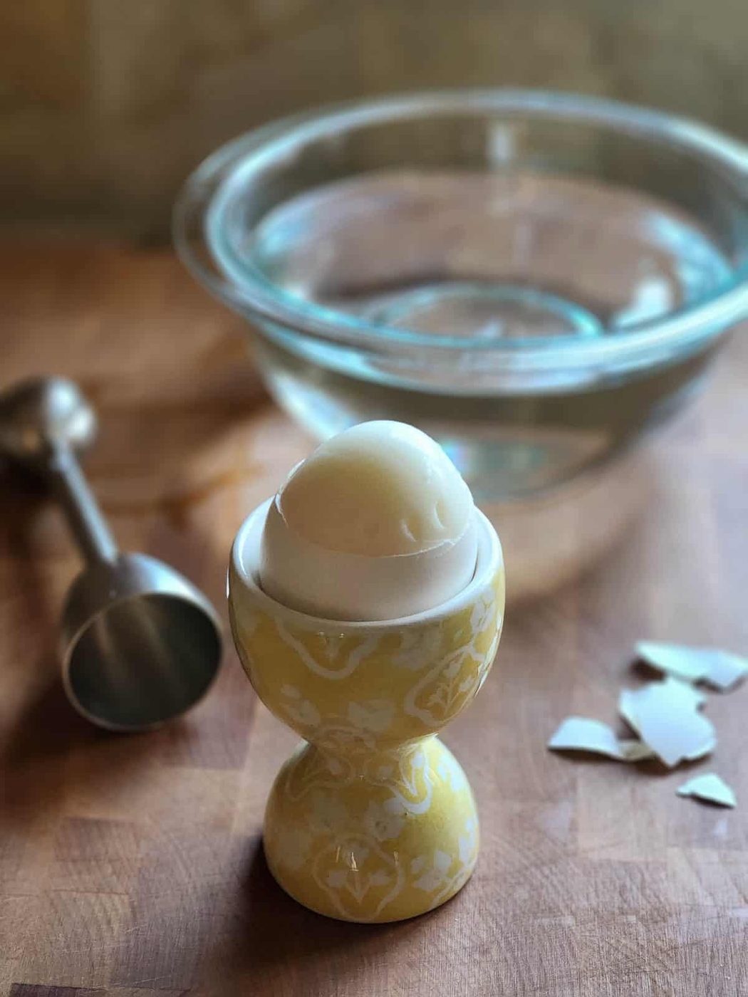 Soft boiled egg in a yellow cup with the top shell removed.