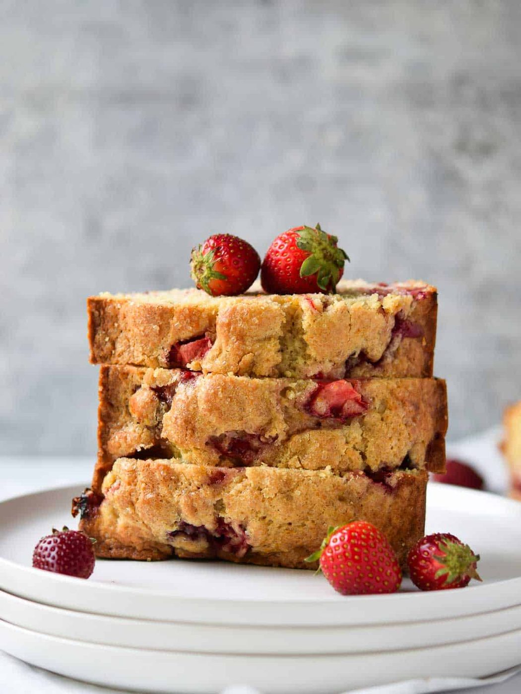 Strawberry bread sliced and stacked on a white plate.