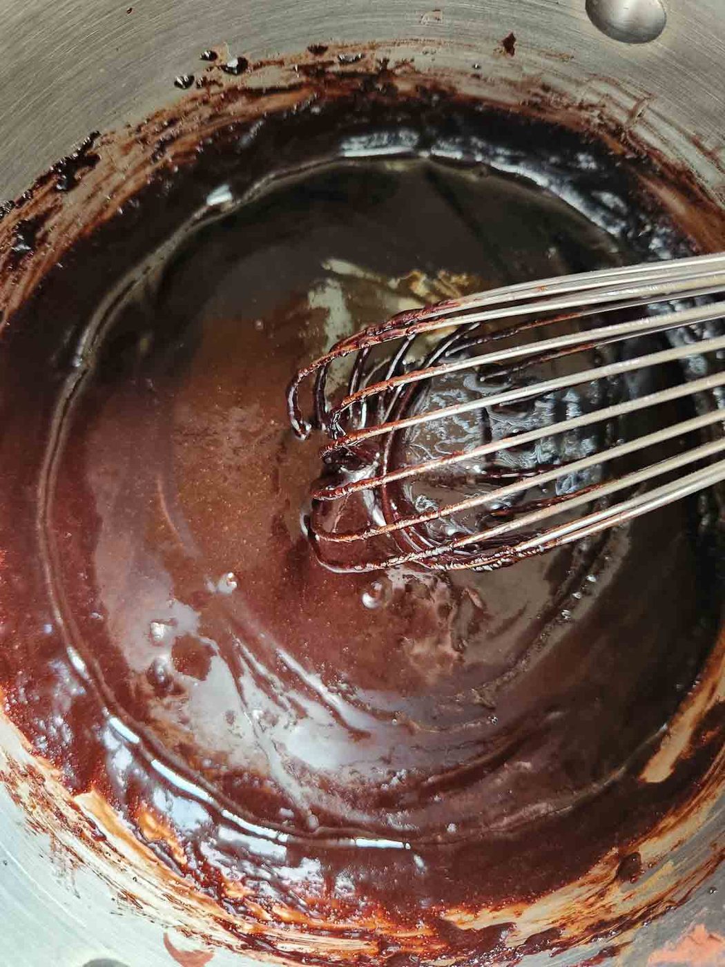 Brownie batter in a metal bowl with a whisk.