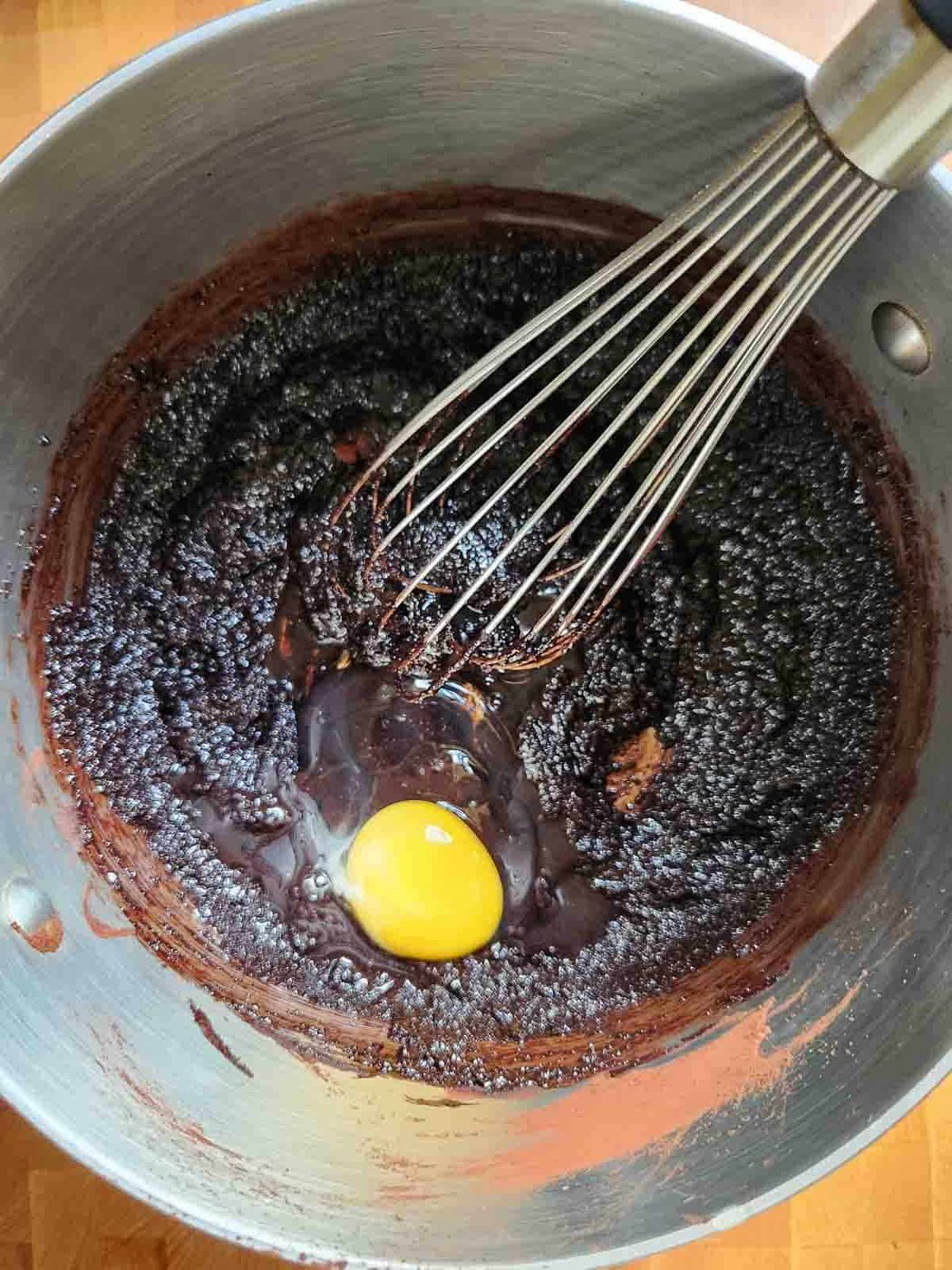 Brownie batter in a meatal bowl with a whisk.