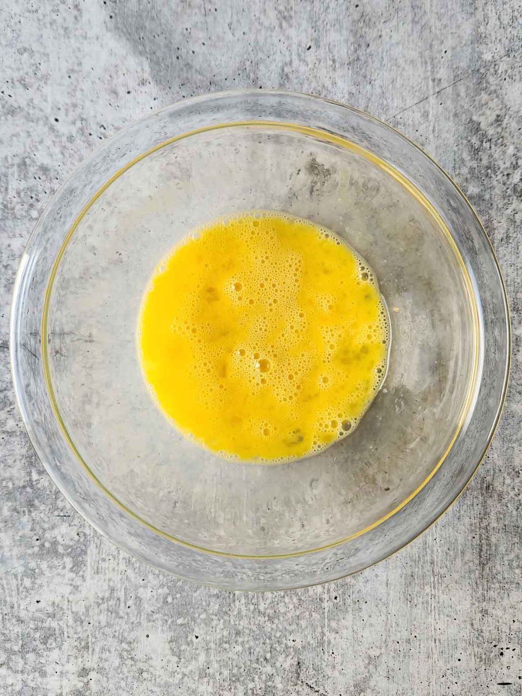 Whisked eggs in a clear bowl.