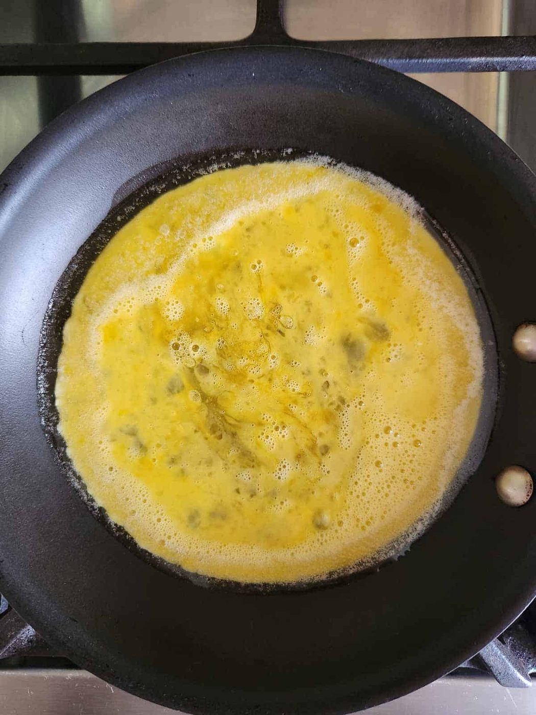 Whisked eggs in a small black pan.