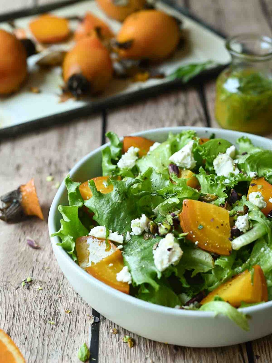Eye-level view of golden beet salad in a white bowl on a wood surface.