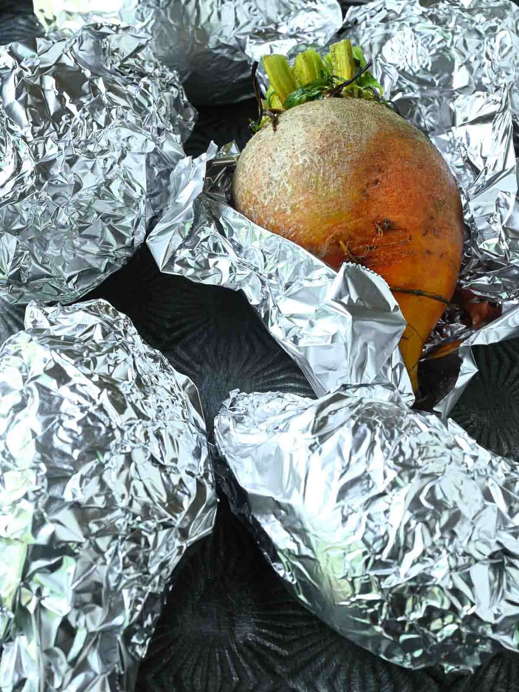 Beets wrapped in foil, with one beet showing.