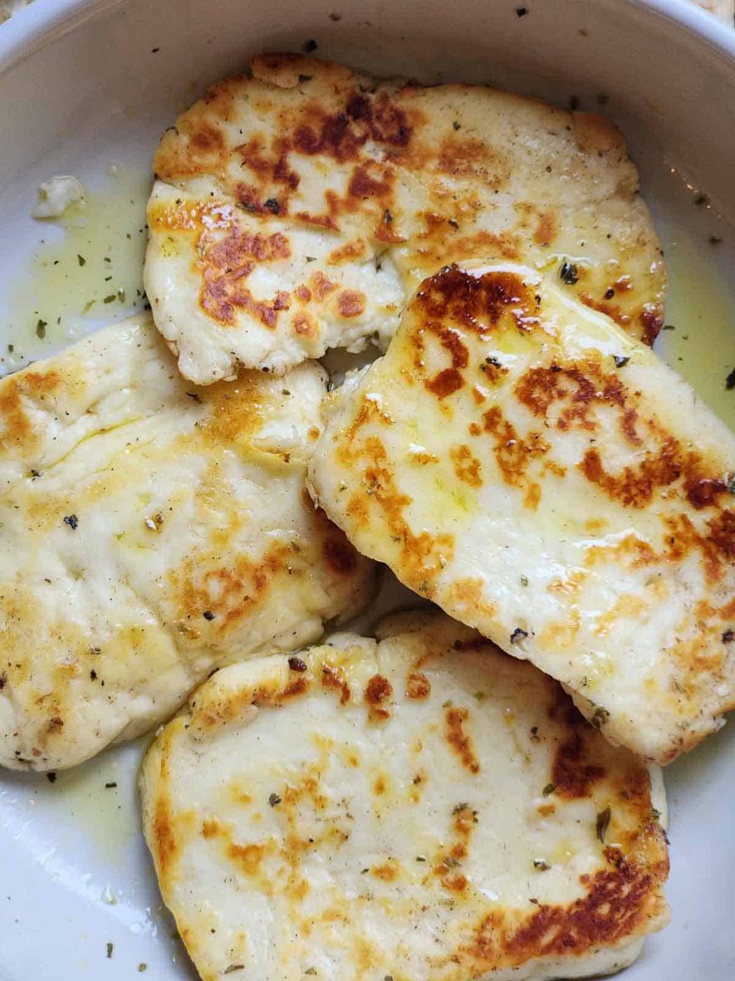 Fried halloumi cheese in a white bowl.