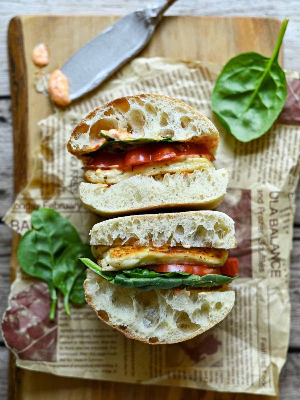 Flat view of two halloumi sandwiches on a cutting board with lettuce beside it.