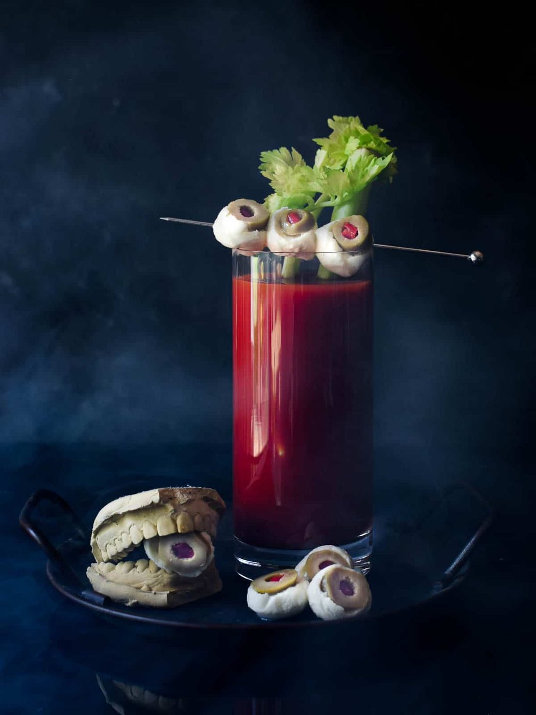 Bloody Mary with celery and mozzarella garnish on a black background.
