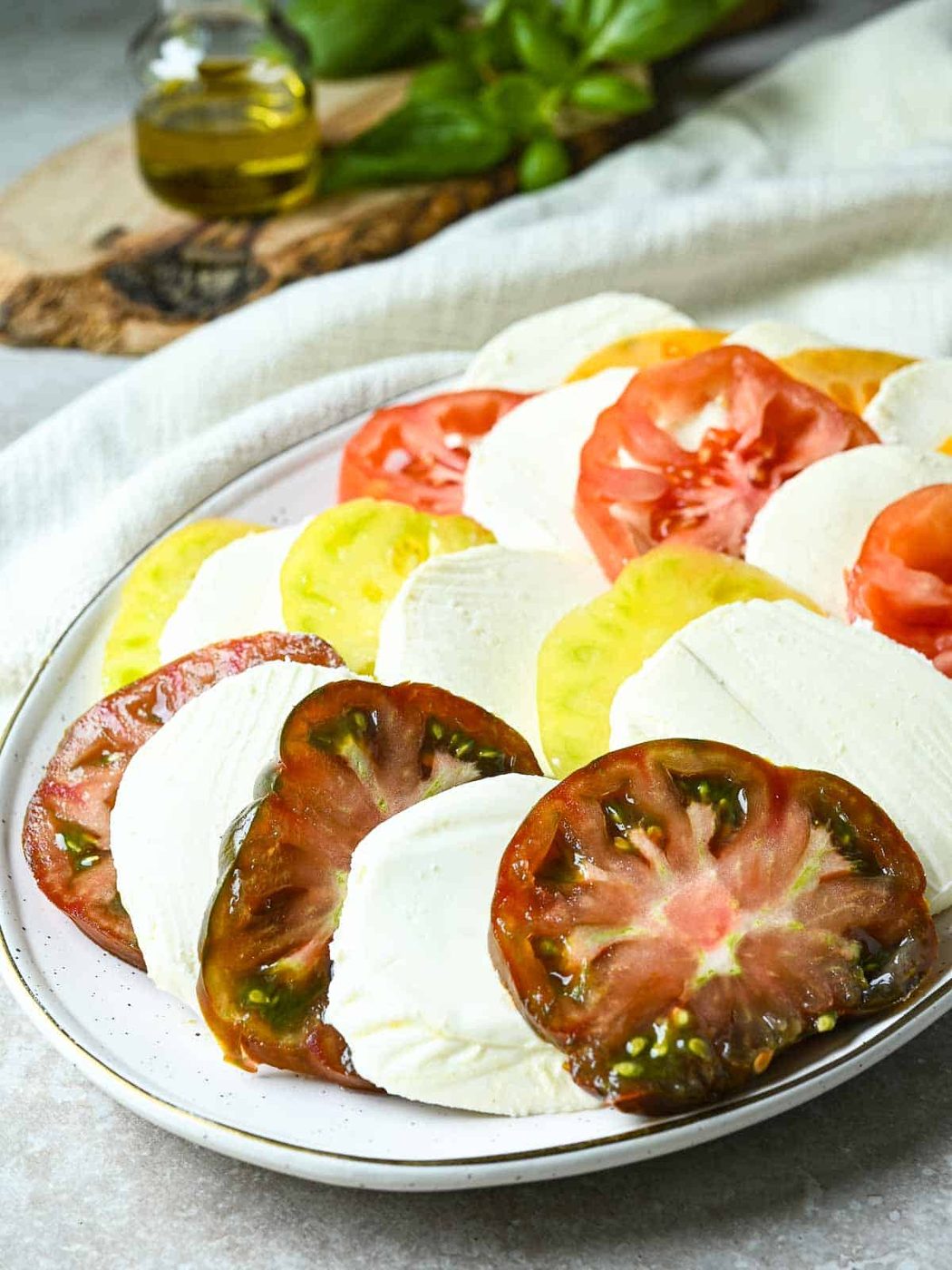 Sliced heirloom tomatoes and mozzarella on a white platter.