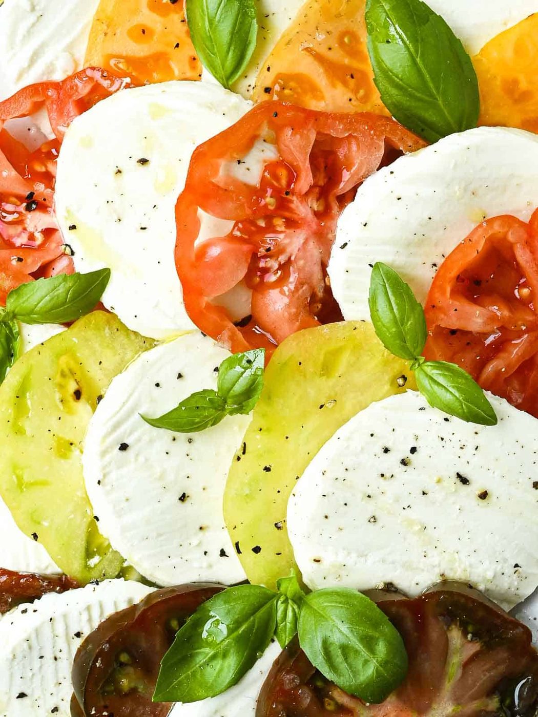 Close-up of sliced tomatoes, mozzarella, and basil.