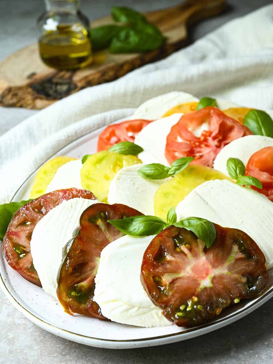 Sliced tomatoes in different colors layered with mozzarella slices.
