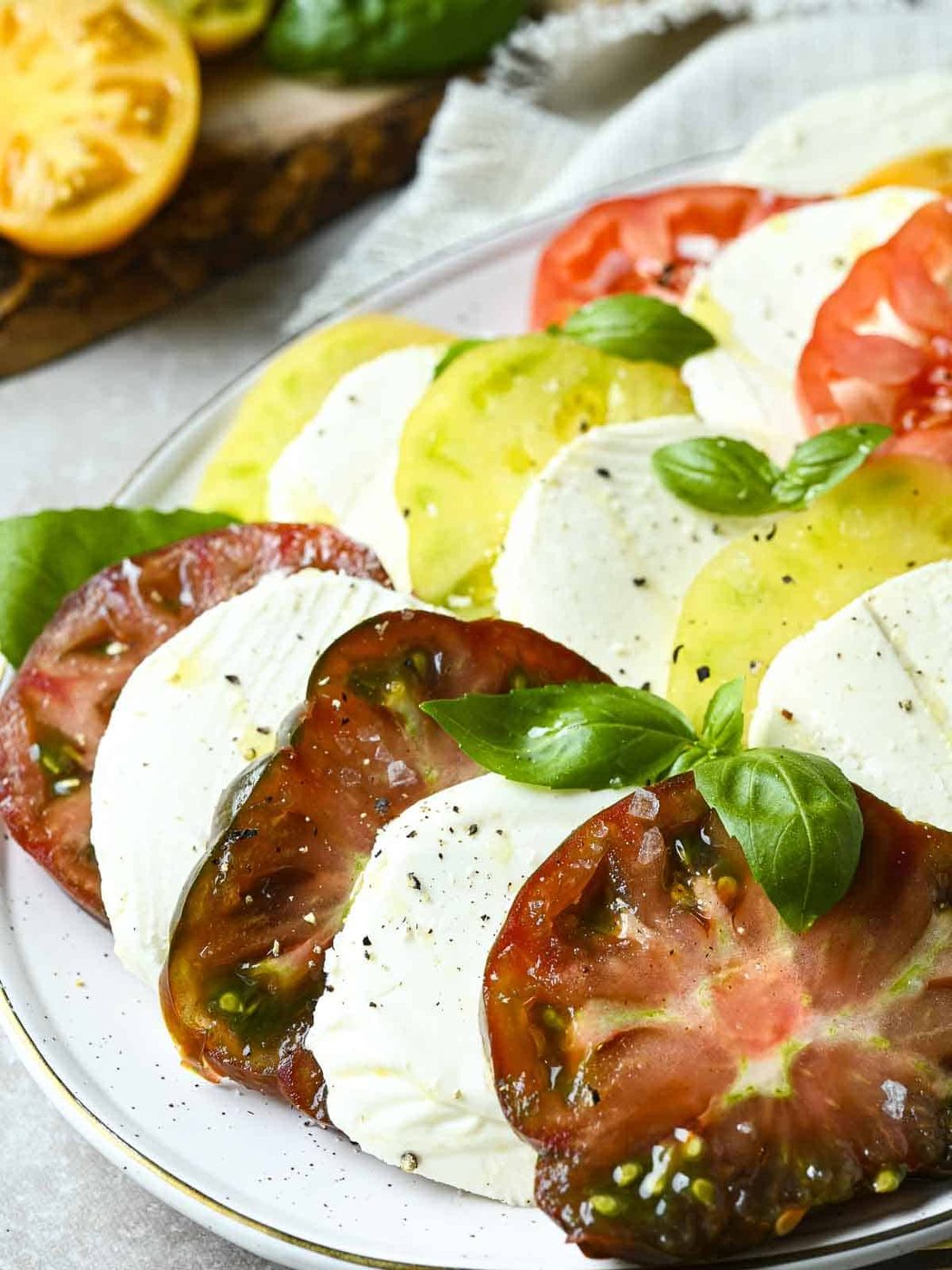 Italian heirloom tomato Caprese salad on a white plate with basil.