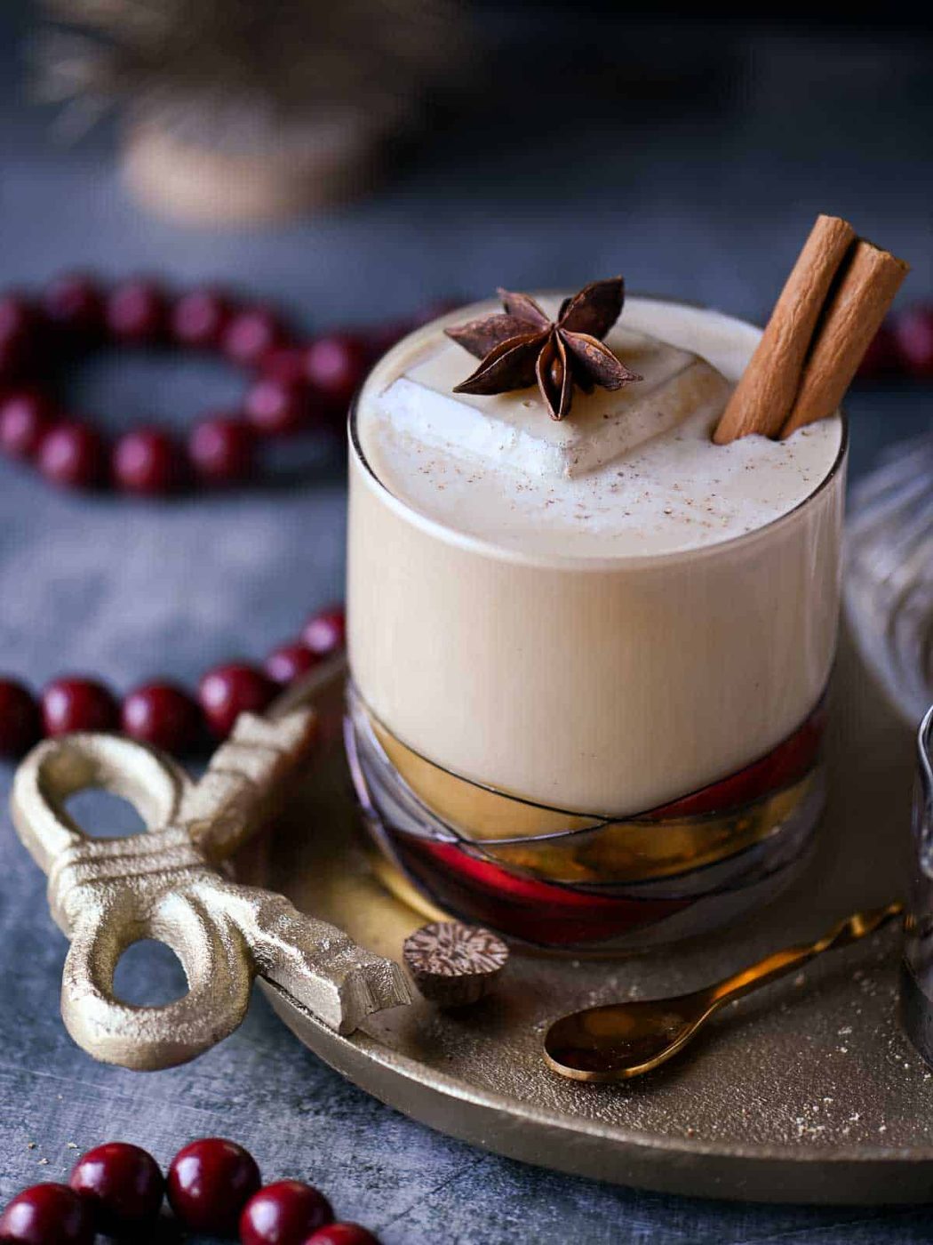 Close-up of a white Russian cocktail with star anise and cinnamon stick on top.