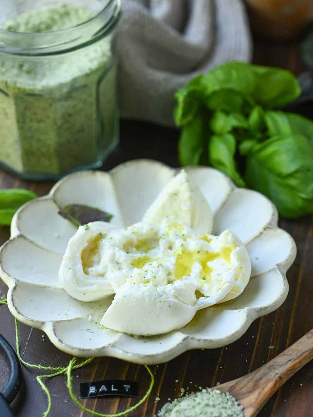 A plate of burrata cheese with oil and green basil salt.