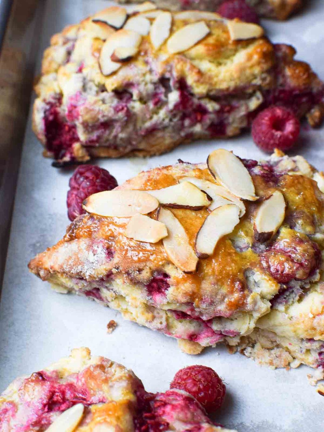 Close-up of raspberry almond scones on parchment paper.