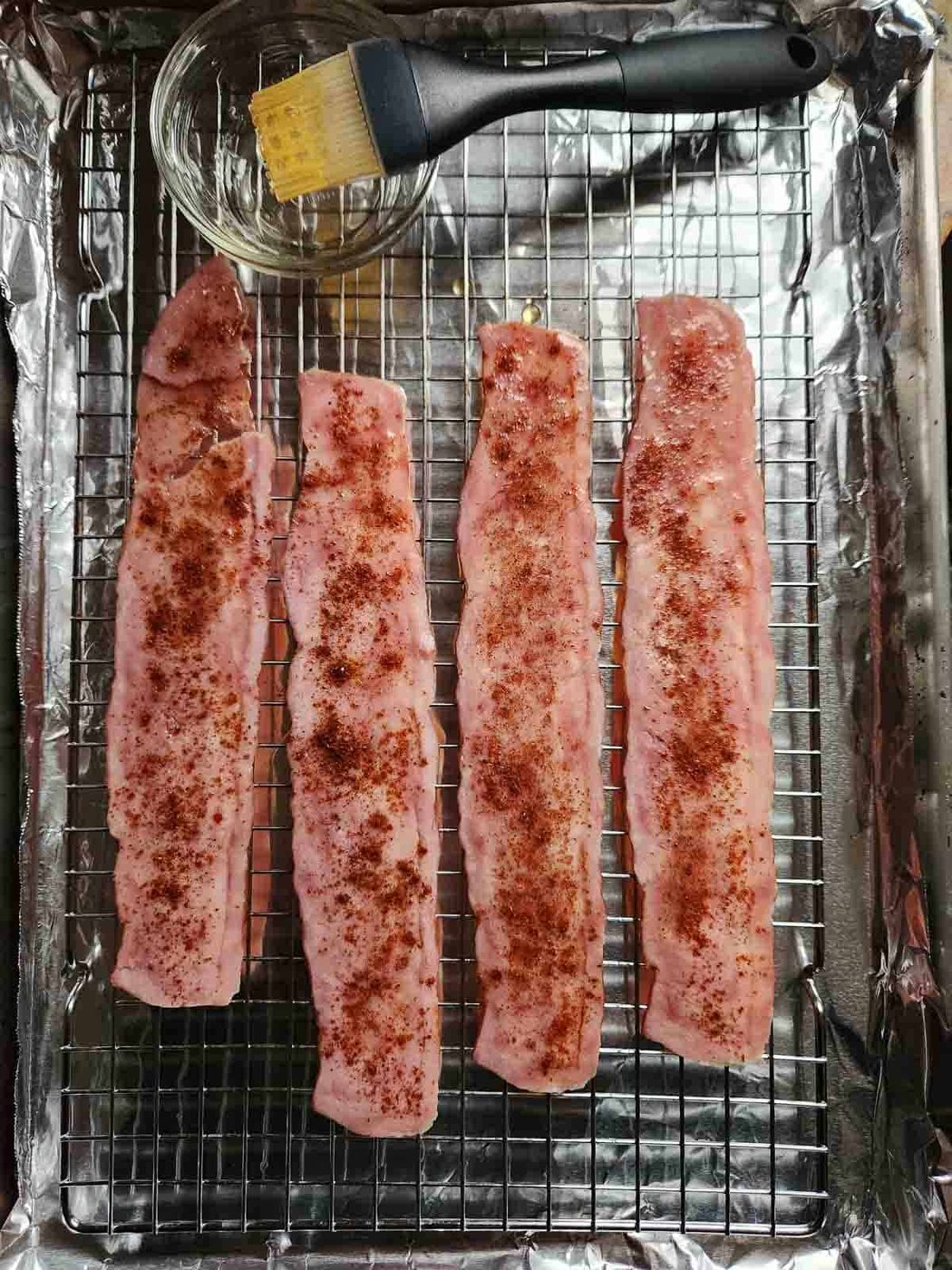 Turkey bacon on a baking pan with chipotle seasoning on top.