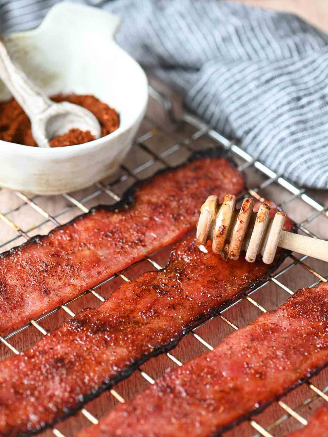 Turkey bacon on a rack with a spoon dipped in honey.