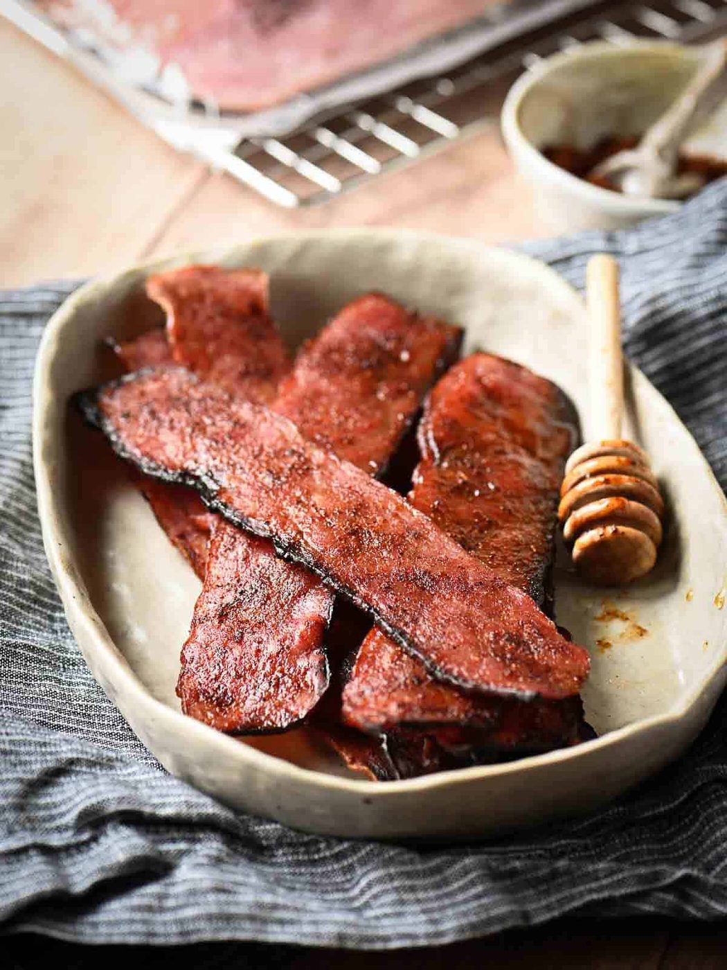 Strips of turkey bacon in a beige bowl on top of a blue napkin.