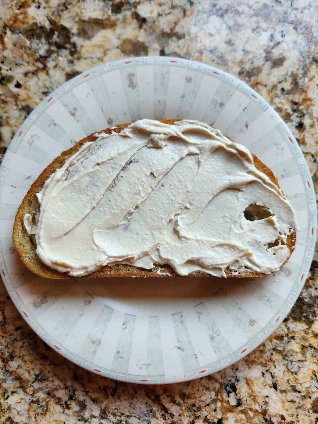 Hummus spread on toast on a round plate.