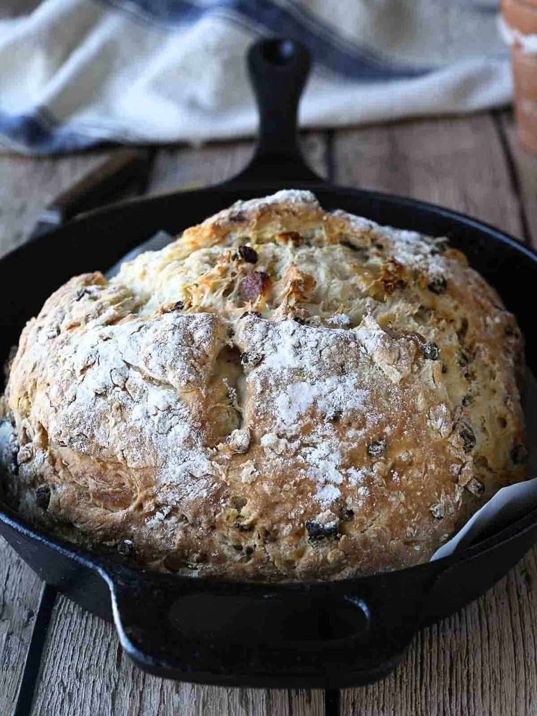 Irish soda bread in a cast iron skillet on a wood surface.