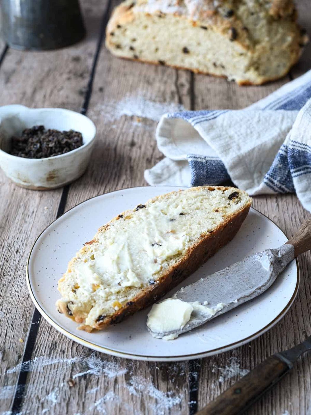 A slice of Irish Soda Bread and Currants and Apricots in the background.