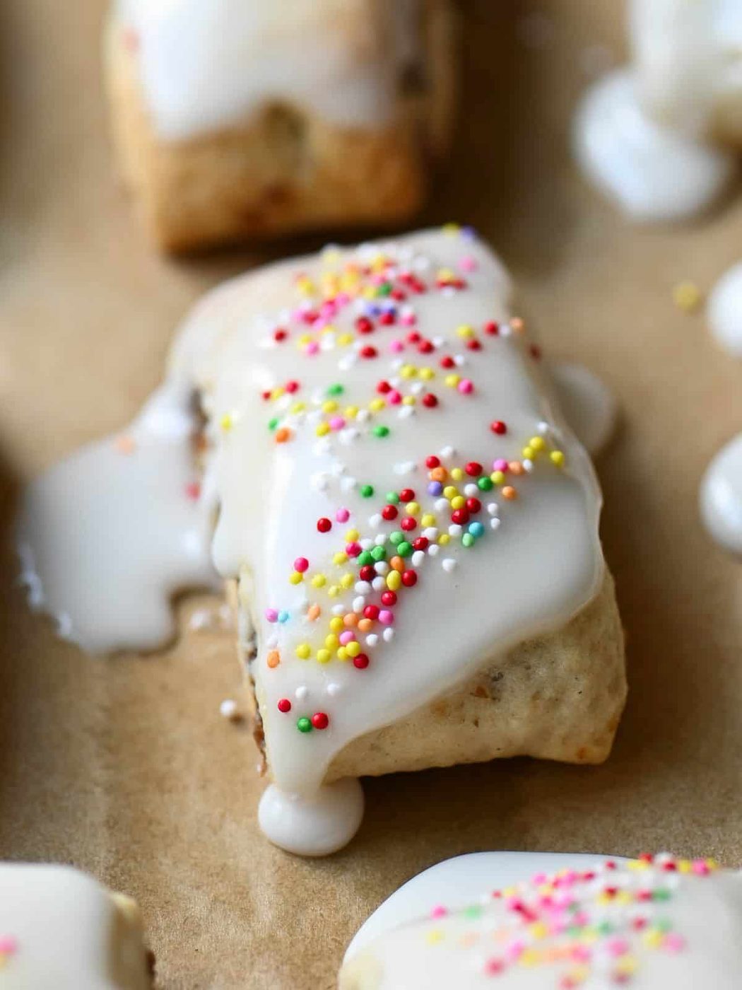 Close up of a fig cookie with white icing and colored sprinkles.