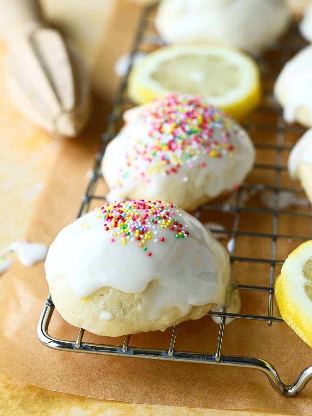 Close-up of Italian lemon drop cookies on a wire rack with multi-colored sprinkles on top.