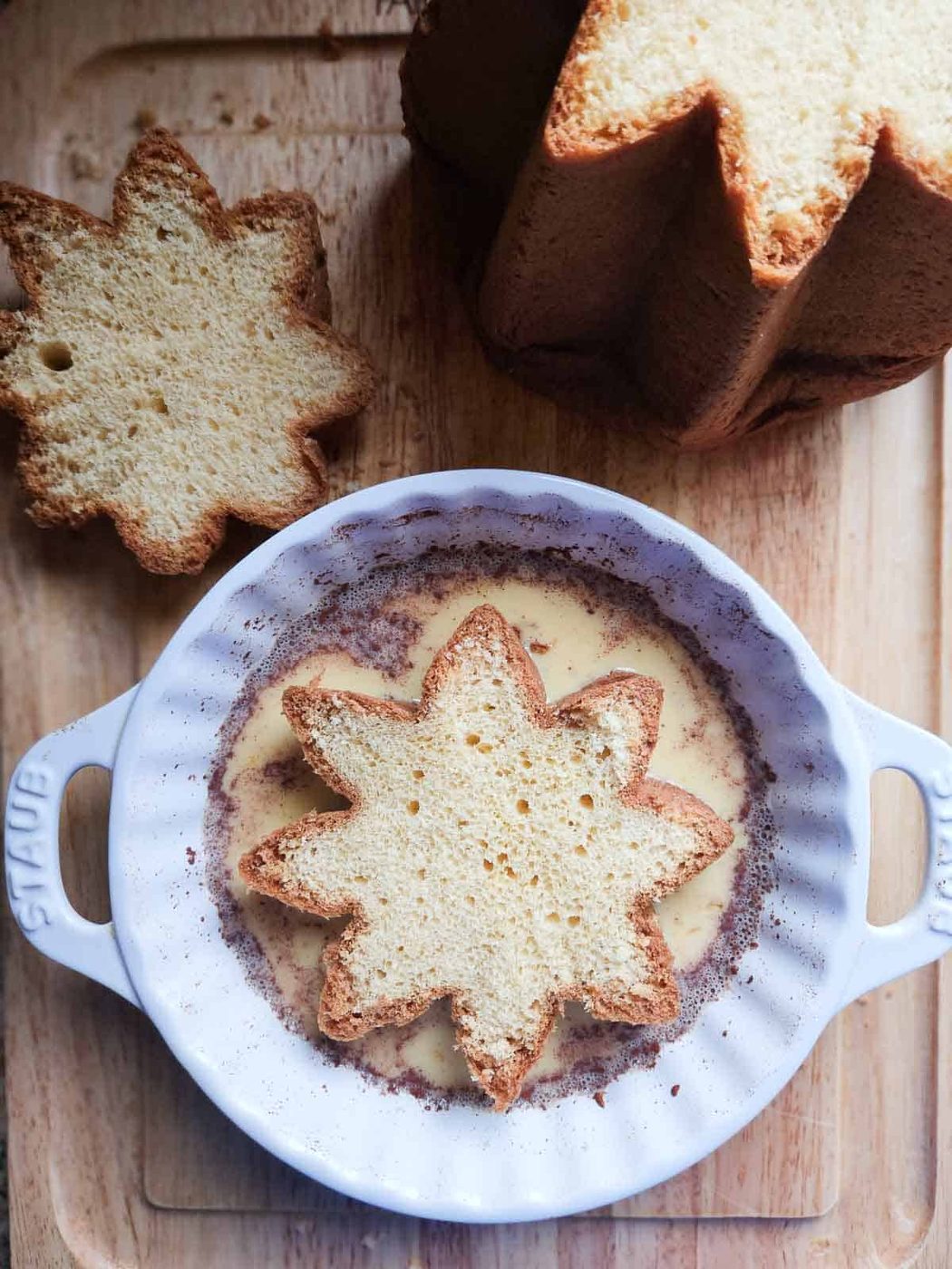 A slice of pandoro in french toast custard in a white dish.